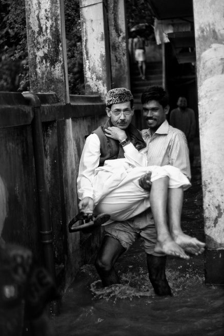 一位阿訇在其他人的帮助下离开被水围困的清真寺.