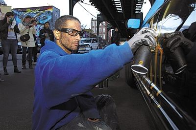 一名涂鸦艺术家在自己的车上喷漆声援"涂鸦保卫战"