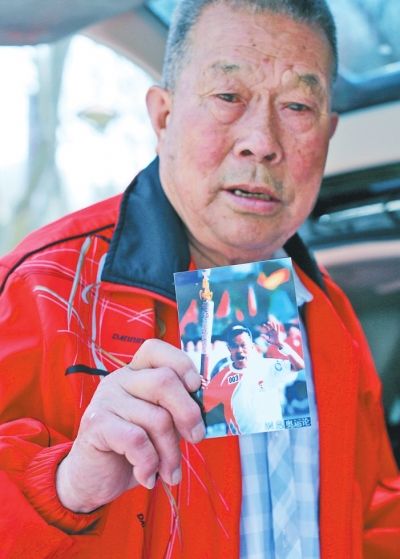 张亮友展示2008年参加北京奥运火炬传递时的照片