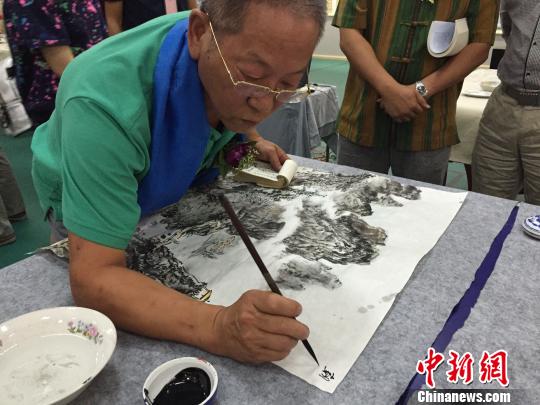 图为张荣在现场挥毫作画. 董乐 摄